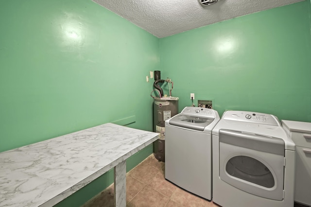 laundry room with a textured ceiling, light tile patterned floors, electric water heater, laundry area, and washer and dryer