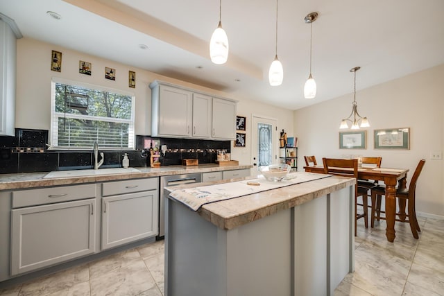 kitchen with tasteful backsplash, gray cabinets, a sink, and light countertops