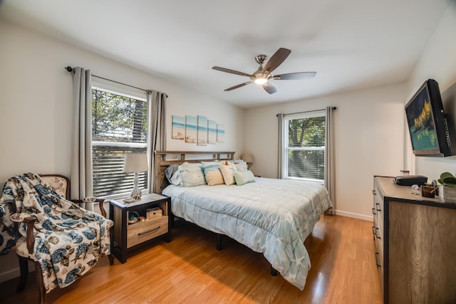 bedroom with ceiling fan, light wood finished floors, multiple windows, and baseboards