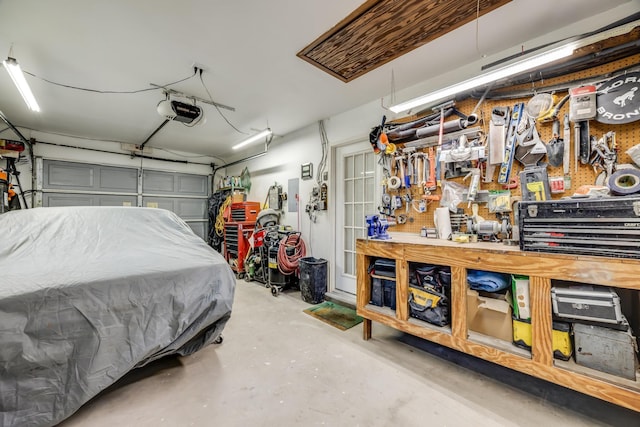 garage featuring electric panel, a workshop area, and a garage door opener