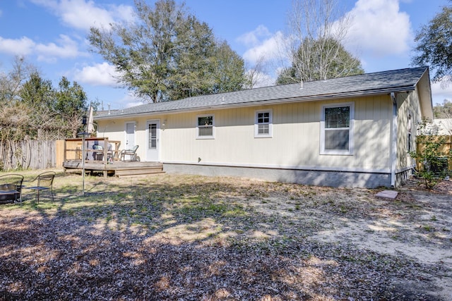 back of house with a fire pit, a wooden deck, and fence