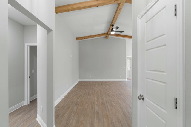 spare room featuring lofted ceiling with beams, light wood-style flooring, baseboards, and ceiling fan