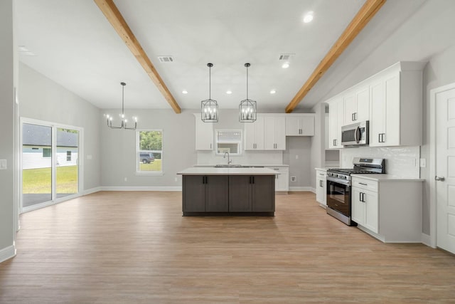 kitchen with tasteful backsplash, visible vents, beamed ceiling, stainless steel appliances, and light countertops