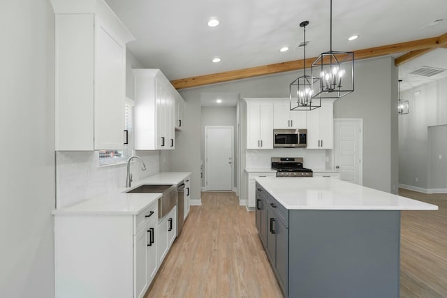 kitchen featuring stainless steel microwave, range, a sink, and beamed ceiling