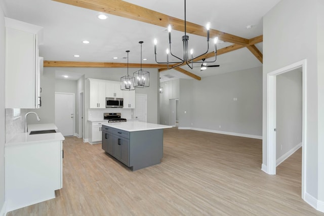 kitchen with stainless steel appliances, a sink, white cabinets, a center island, and beamed ceiling