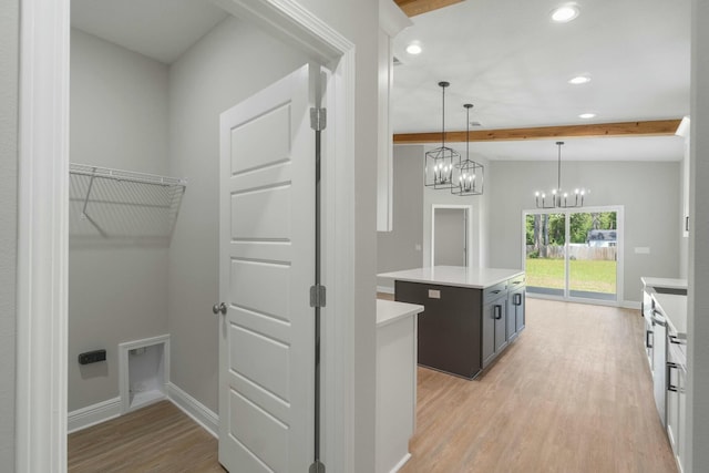 kitchen with light countertops, beamed ceiling, light wood-style flooring, and a center island