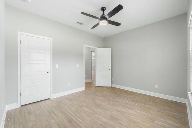 unfurnished bedroom featuring light wood finished floors, a ceiling fan, visible vents, and baseboards