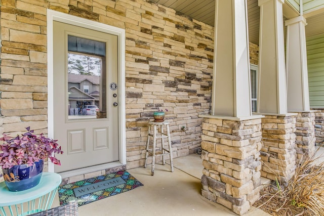 entrance to property with stone siding and a porch