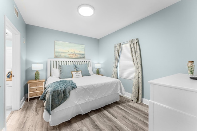 bedroom with wood finished floors, visible vents, and baseboards