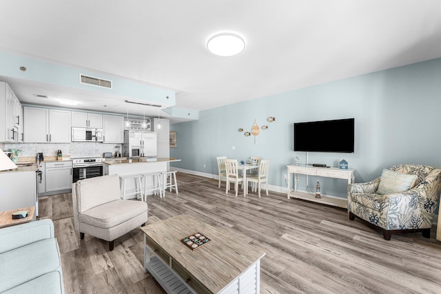 living area with baseboards, visible vents, and light wood finished floors