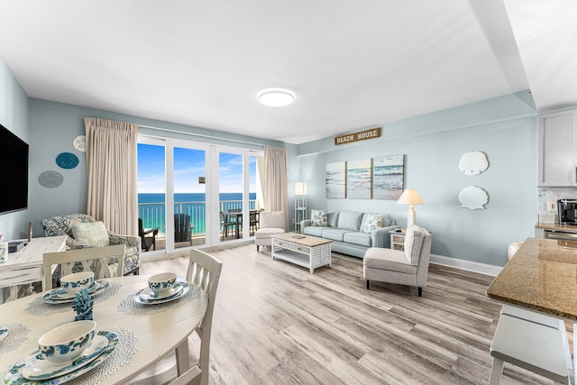 living area featuring baseboards, a water view, and light wood-style floors