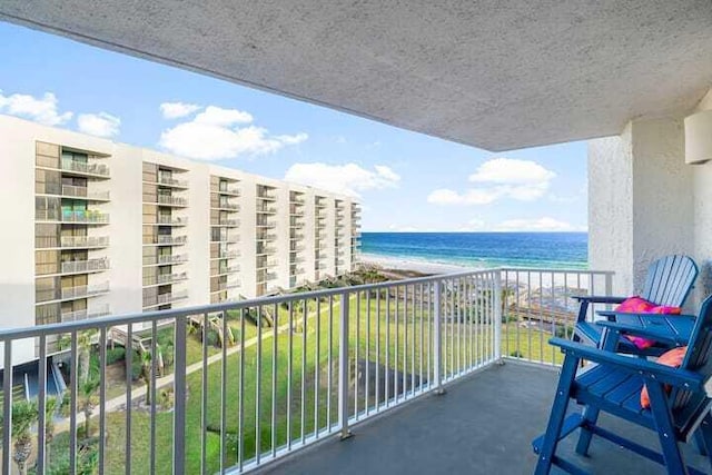 balcony with a water view and a view of the beach