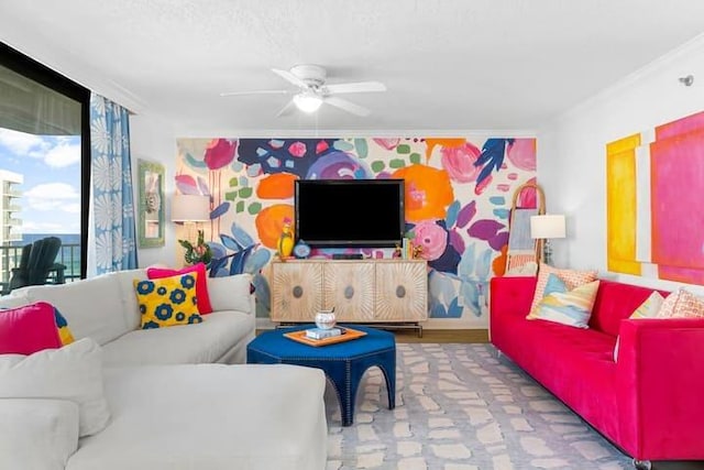 living room with ceiling fan, an accent wall, and ornamental molding