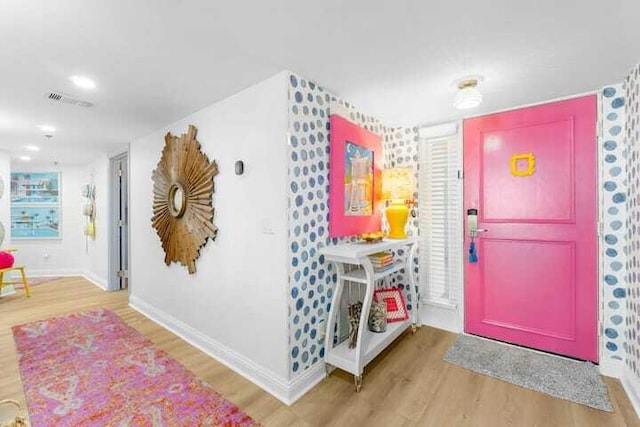 foyer featuring baseboards, visible vents, and wood finished floors