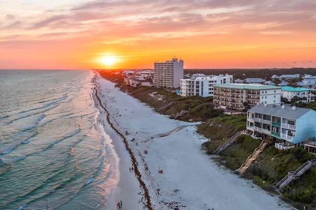 aerial view at dusk featuring a water view and a view of the beach