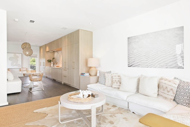 living area featuring visible vents and wood finished floors