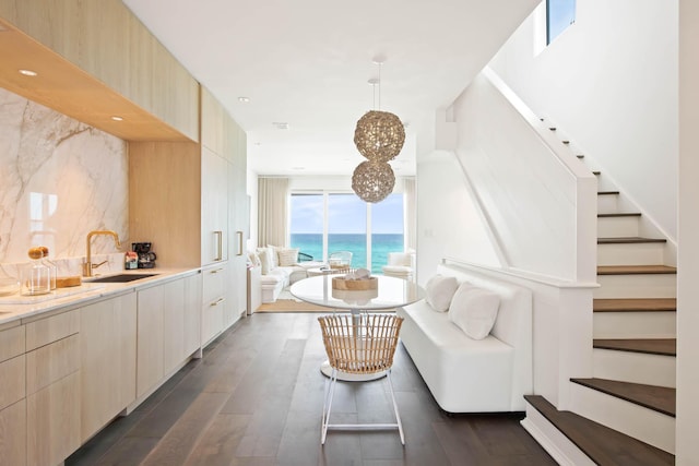 interior space featuring dark wood-style floors, stairway, a water view, and a notable chandelier