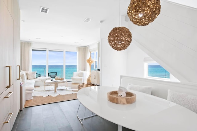 dining room featuring a water view, visible vents, a chandelier, and wood finished floors