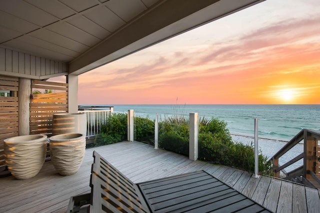 deck at dusk featuring a water view and a view of the beach