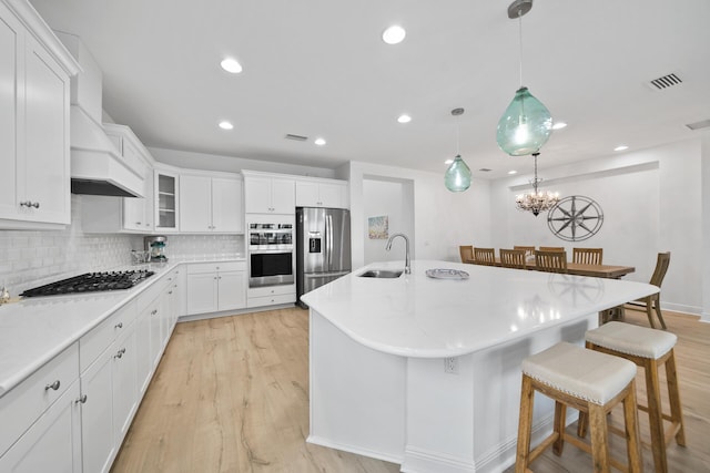 kitchen featuring a breakfast bar area, a sink, visible vents, appliances with stainless steel finishes, and custom exhaust hood