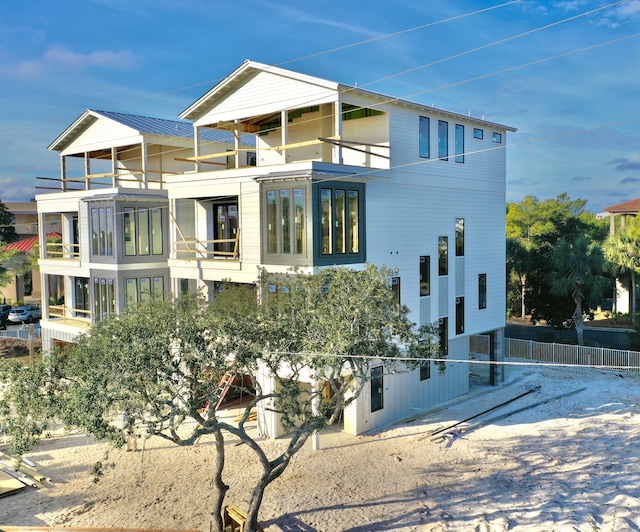 view of property exterior with a balcony, fence, and metal roof