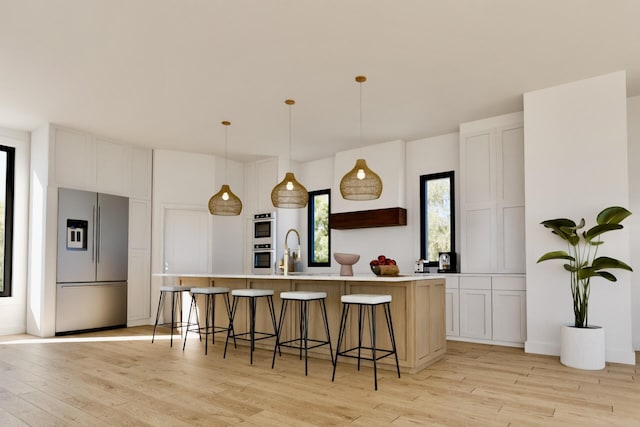 kitchen with light countertops, a kitchen breakfast bar, appliances with stainless steel finishes, light wood-style floors, and a sink