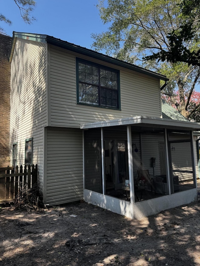 rear view of house with a sunroom and fence