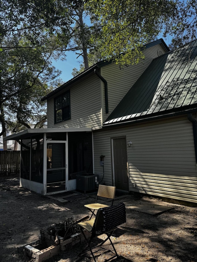 back of house with a sunroom, central AC, metal roof, a standing seam roof, and fence