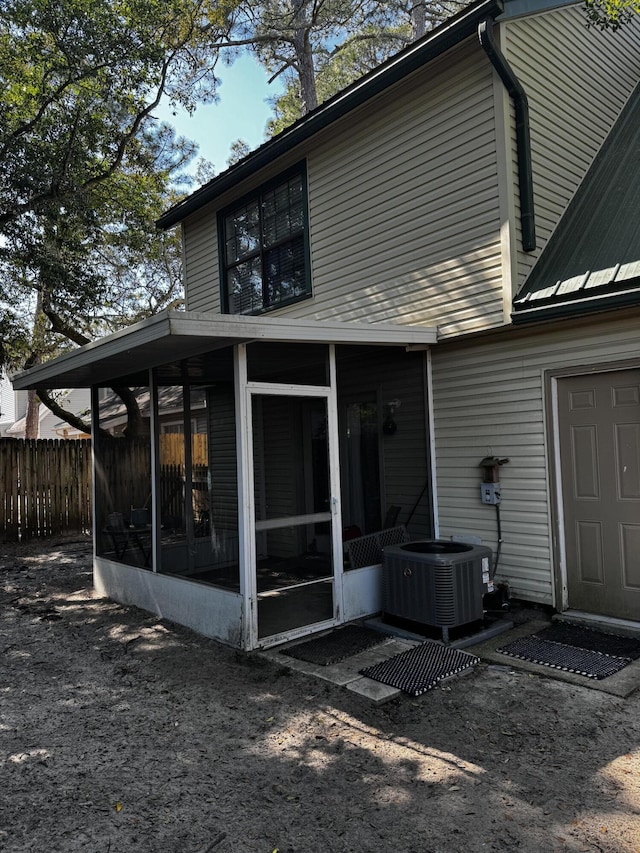 rear view of house with a sunroom, fence, and cooling unit