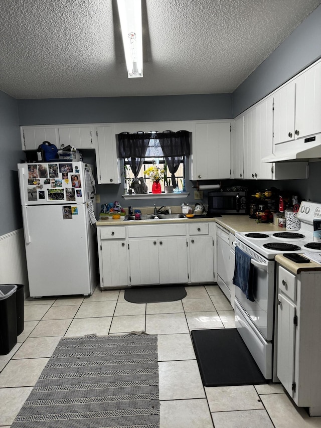 kitchen featuring white appliances, under cabinet range hood, a sink, and light tile patterned flooring