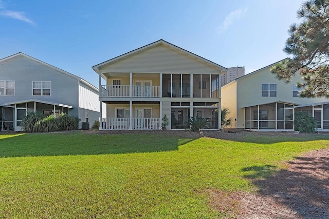 rear view of property featuring central AC unit, a lawn, and a sunroom