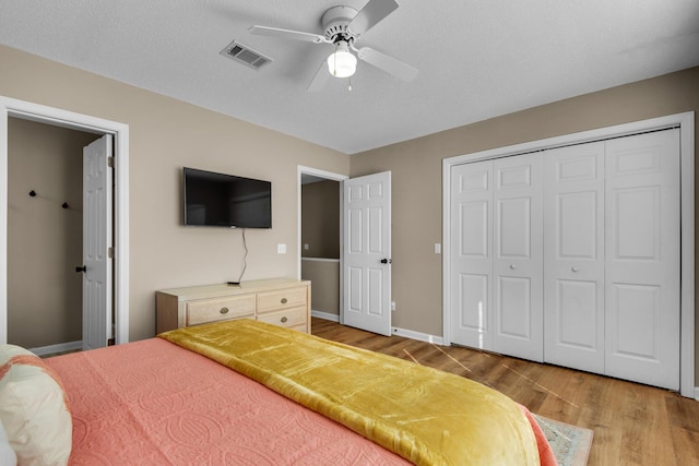 bedroom featuring a closet, visible vents, light wood-style floors, a ceiling fan, and baseboards