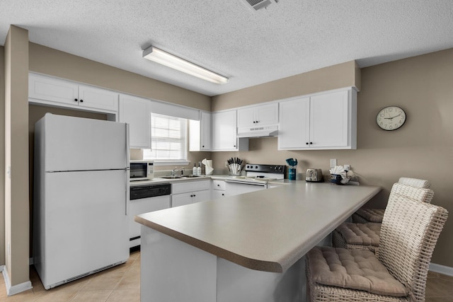 kitchen with white appliances, white cabinets, a peninsula, under cabinet range hood, and a sink