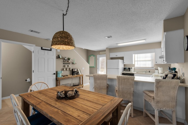 dining space with a textured ceiling, light tile patterned flooring, and visible vents