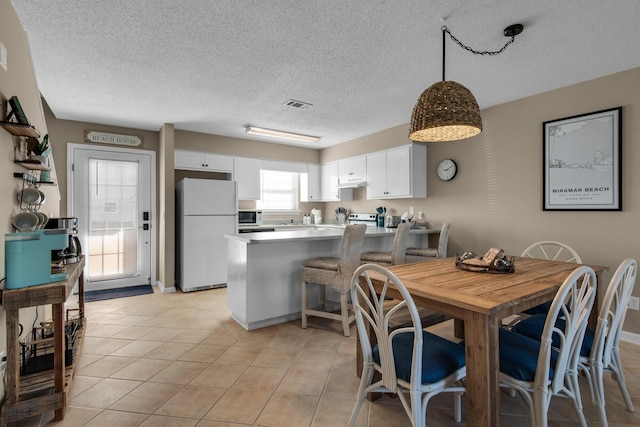 dining room with light tile patterned floors, visible vents, and a textured ceiling