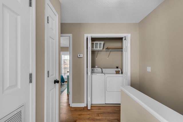 laundry room with a textured ceiling, laundry area, wood finished floors, visible vents, and independent washer and dryer