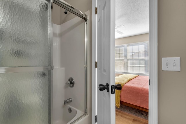 bathroom featuring a textured ceiling, wood finished floors, and enclosed tub / shower combo