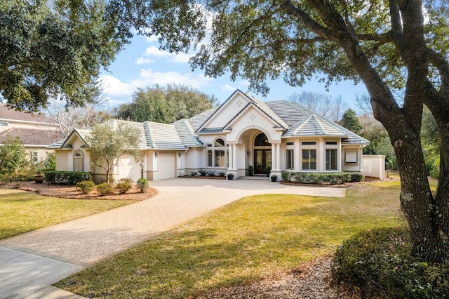 view of front of property featuring a garage, a front yard, decorative driveway, and stucco siding