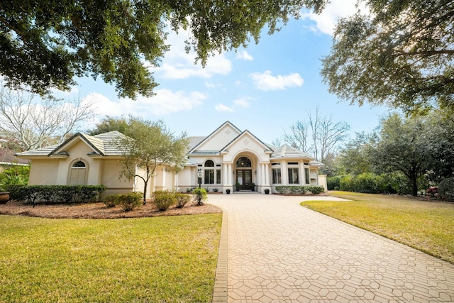 view of front of house featuring decorative driveway, a front yard, and stucco siding