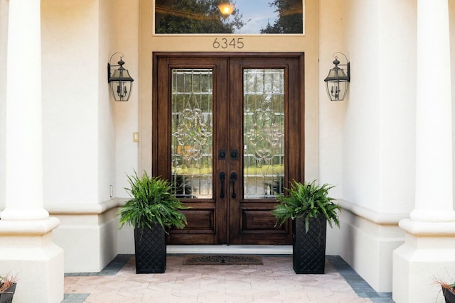 view of exterior entry featuring french doors and stucco siding