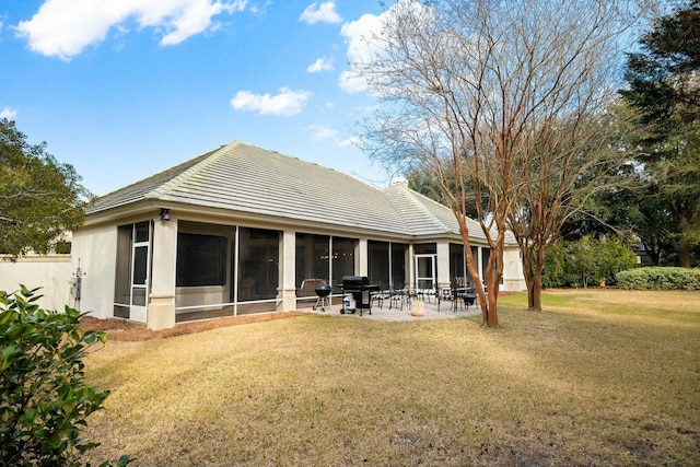 back of house featuring a sunroom, a patio area, stucco siding, and a yard