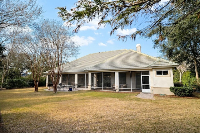 rear view of property with a lawn, a chimney, a tile roof, and a sunroom