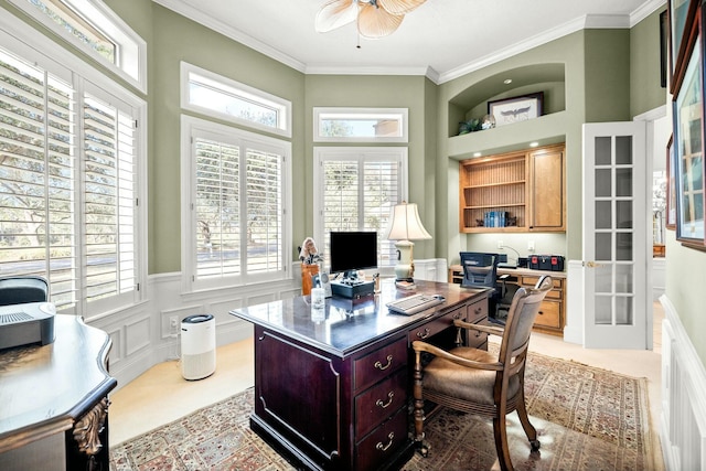 office space with light carpet, wainscoting, a ceiling fan, and crown molding