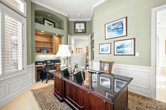 office featuring a wainscoted wall, built in shelves, a decorative wall, and crown molding