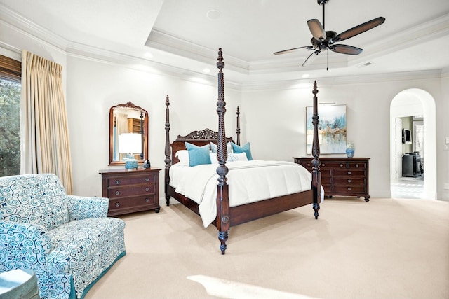 carpeted bedroom with arched walkways, visible vents, a ceiling fan, ornamental molding, and a raised ceiling