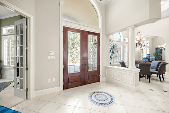 entrance foyer featuring an inviting chandelier, tile patterned floors, crown molding, and french doors