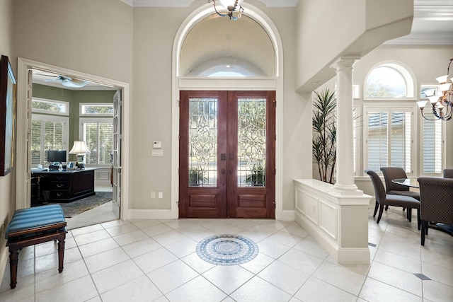 foyer featuring french doors, light tile patterned flooring, decorative columns, and an inviting chandelier