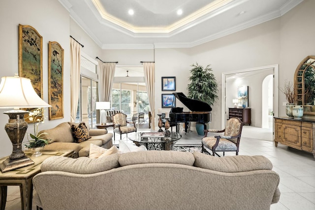 living room featuring light tile patterned floors, arched walkways, a tray ceiling, and ornamental molding