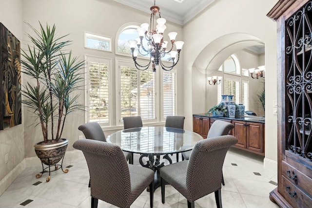 dining room with ornamental molding, a towering ceiling, a wealth of natural light, and an inviting chandelier