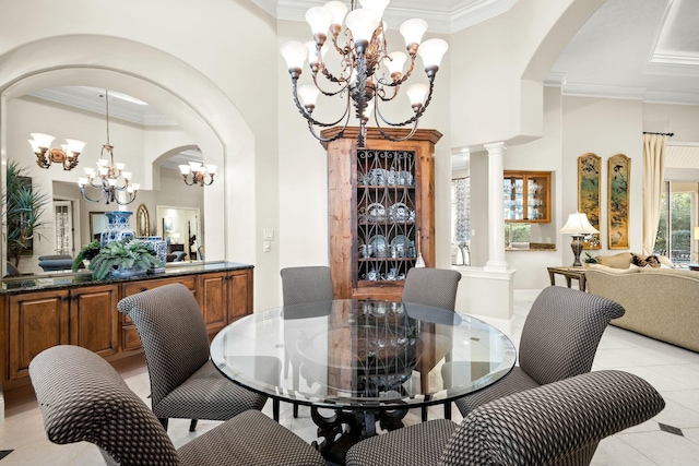 dining area with light tile patterned floors, a notable chandelier, crown molding, a high ceiling, and ornate columns